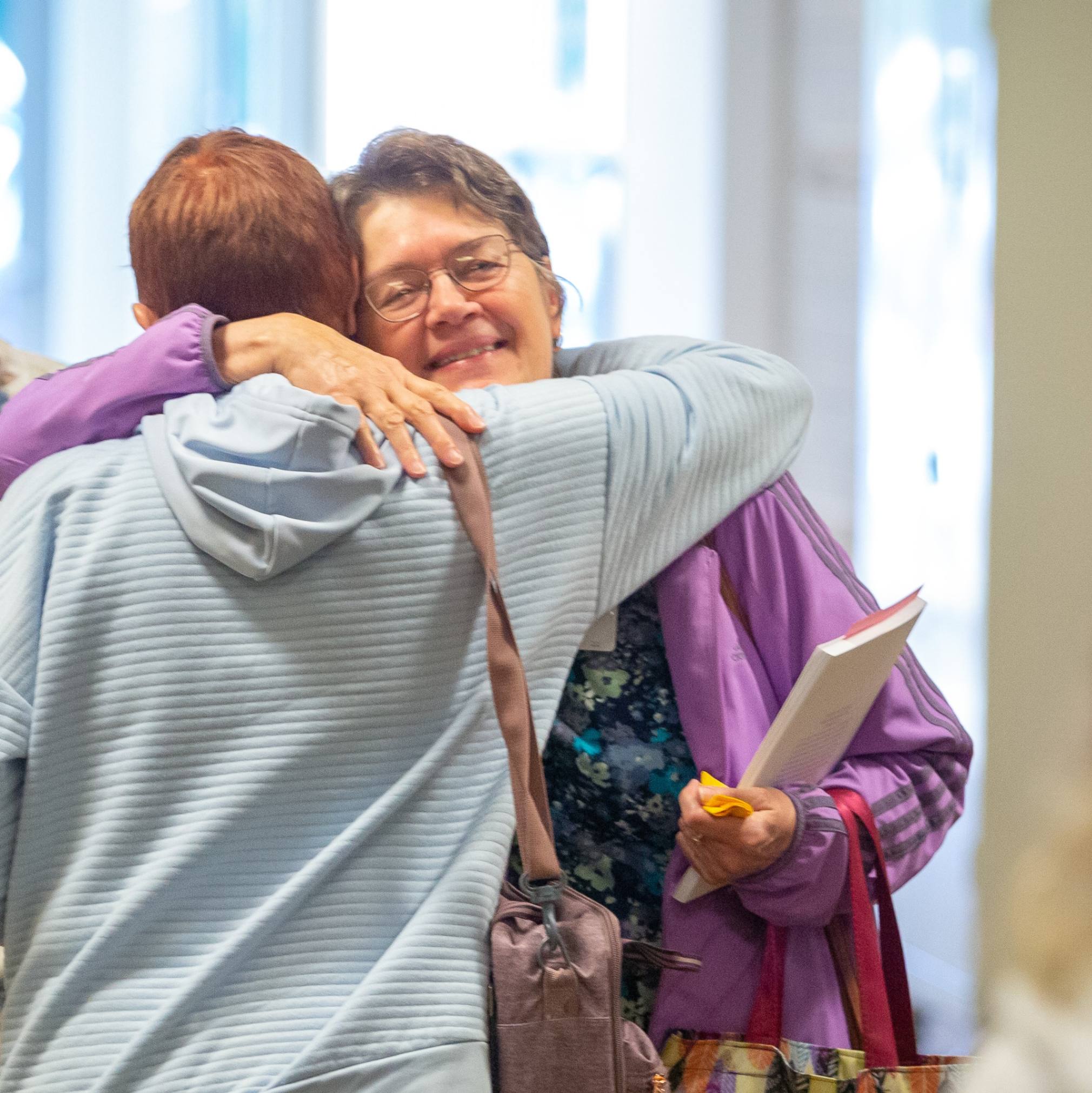 Two women embrace after life groups at church.