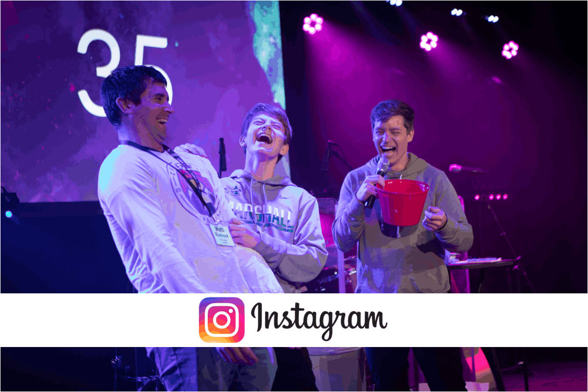 Three people laugh while playing a game on stage.