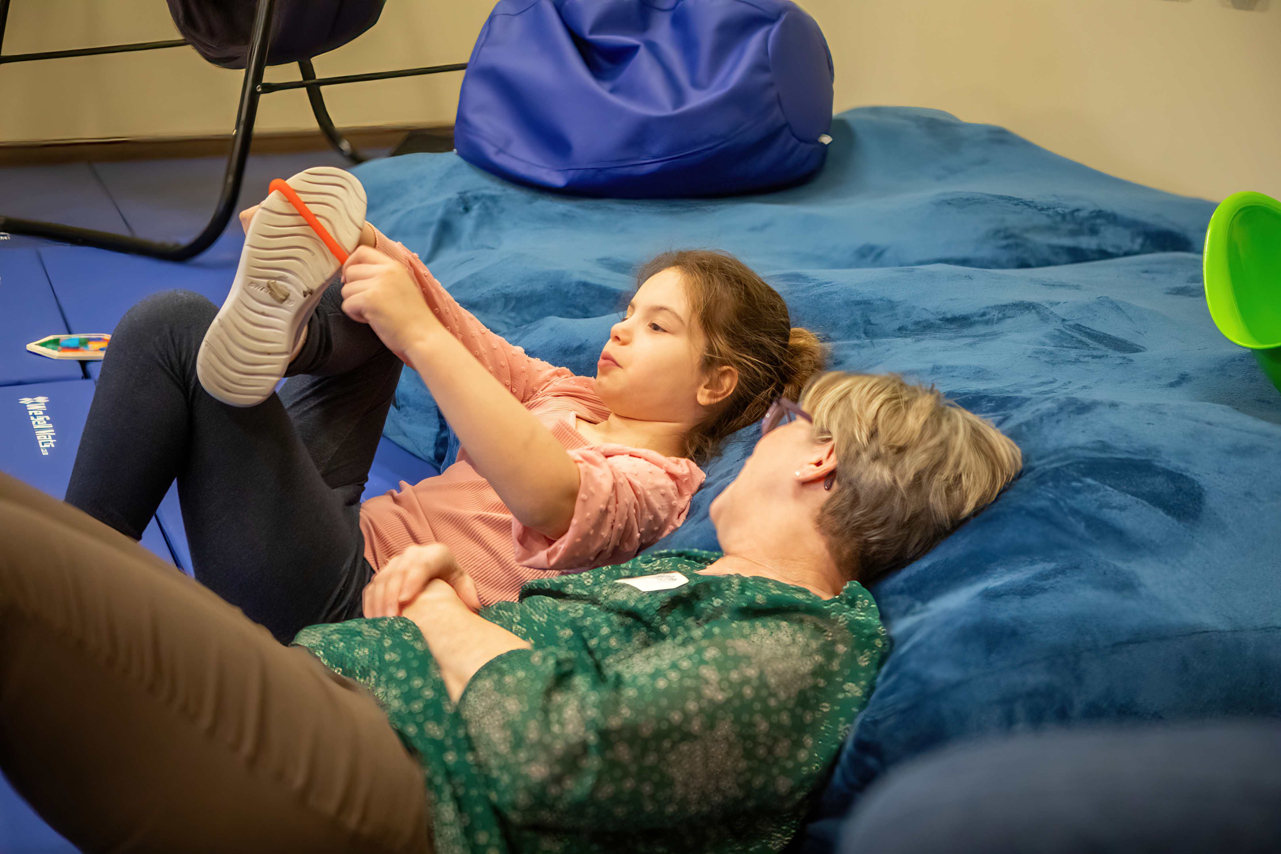 A child and leader lay on the floor and talk.
